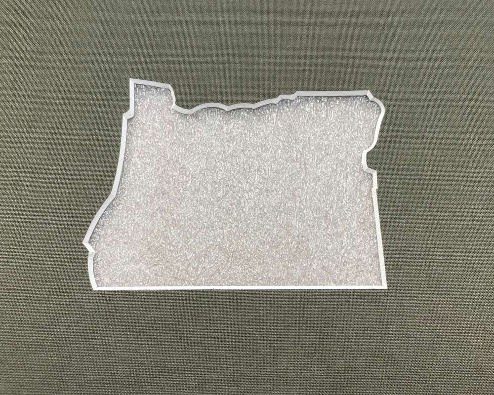 A soft forest green woven mat with a beveled cutout of Oregon.