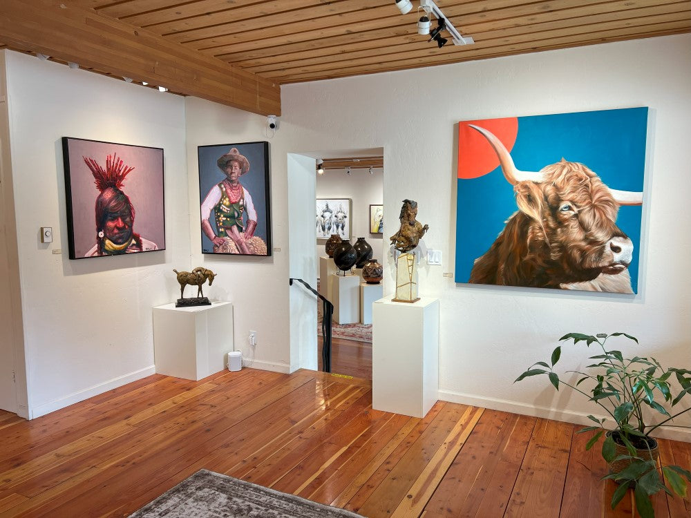 A gallery with white walls, a few plants, and a variety of contemporary artwork from bronze wildlife sculptures and colorful contemporary portraits, to western themes and local Montana landscapes.