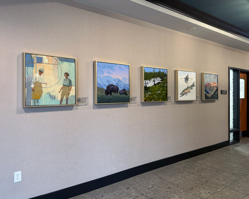 A photo of a wall with five pieces of contemporary western art hung next to plaques of each artist's bios. The artists are Amy Brakeman Livezey, Johne Richardson, Nancy Seiler, Robert Spannring, and JC Spock.