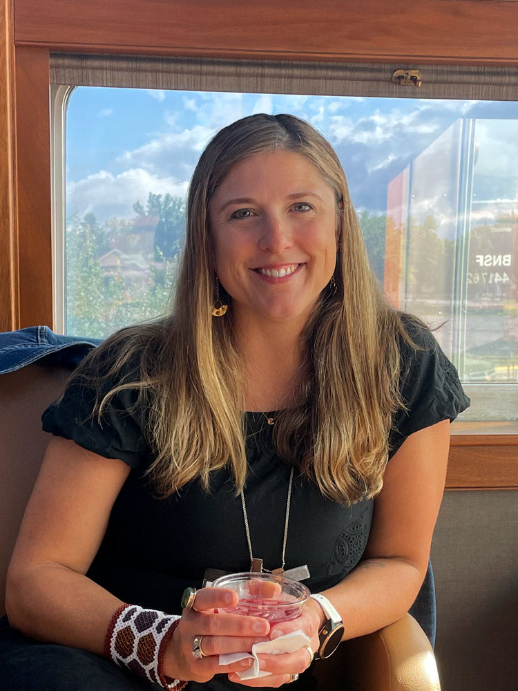 A headshot of a smiling woman with long brown hair wearing a black shirt.