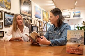 Author Christine Carbo discusses her book in an art gallery.